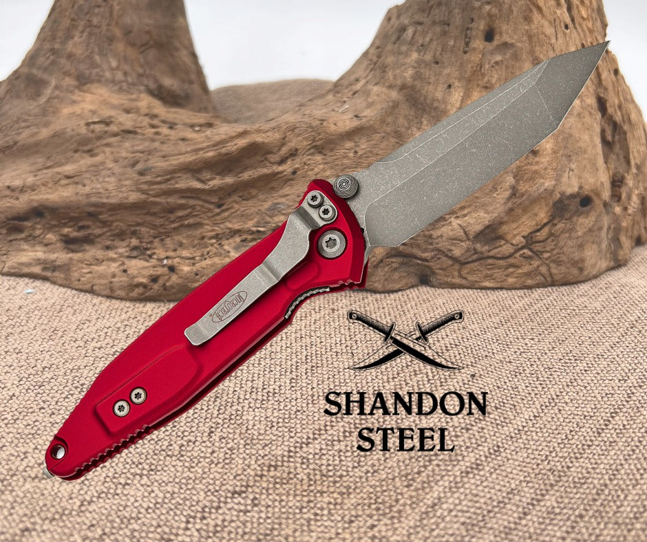 Folding knife with red handle and silver blade on a textured surface with 'Shandon Steel' branding.