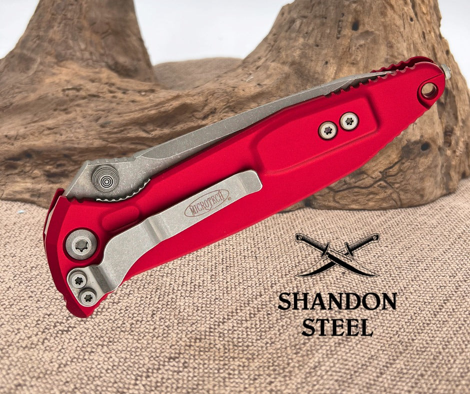 Red folding knife with silver blade on a textured surface, featuring Primemartshop branding.
