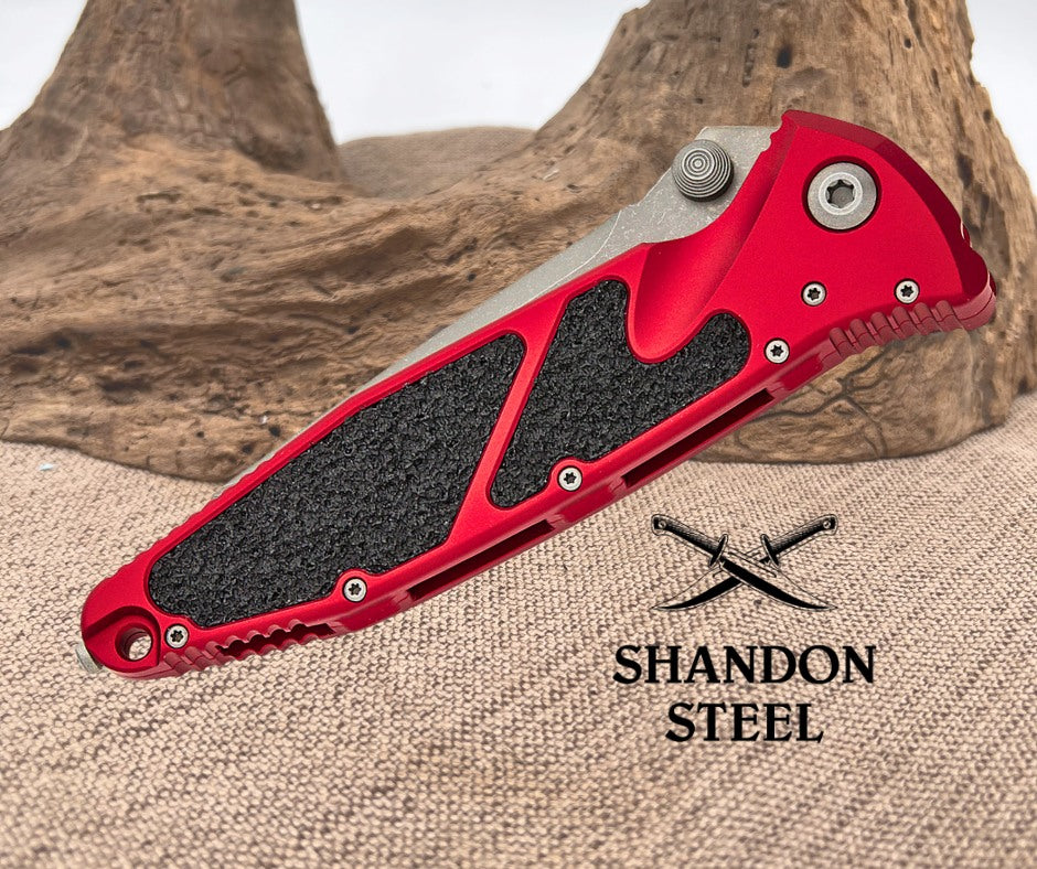 Red folding knife with black grip on a textured surface, featuring the Primemartshop logo.