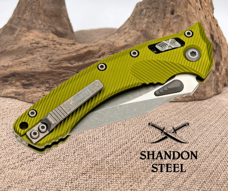 Green folding knife with metallic blade on a textured surface, Primemartshop logo visible