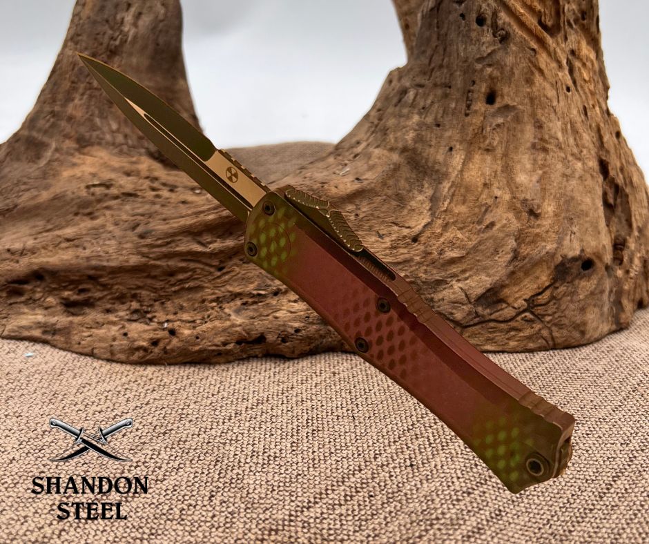 Folding knife with red handle and gold blade on a textured surface, Primemartshop logo visible