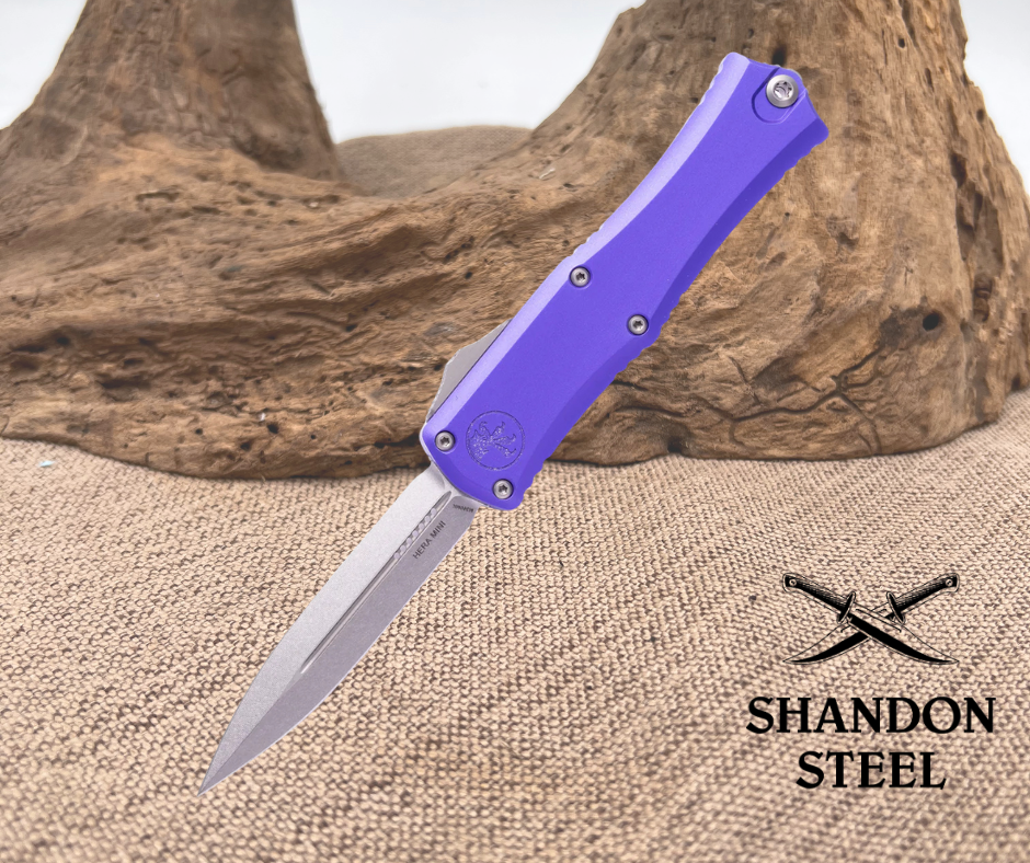 Folding knife with purple handle on a textured surface, Primemartshop branding visible